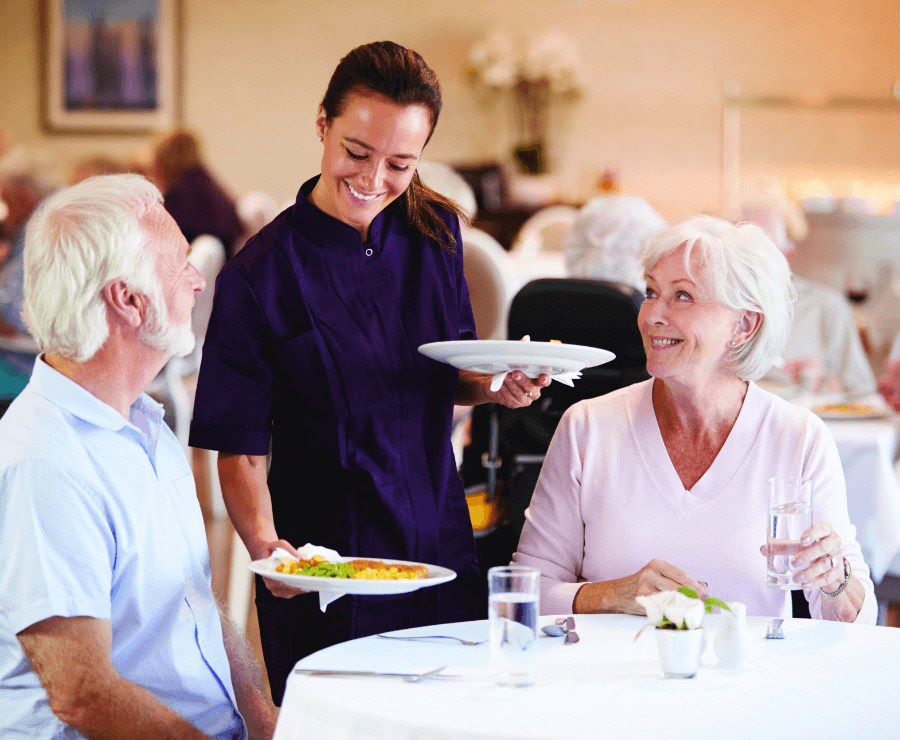waitress serving food to senior couple