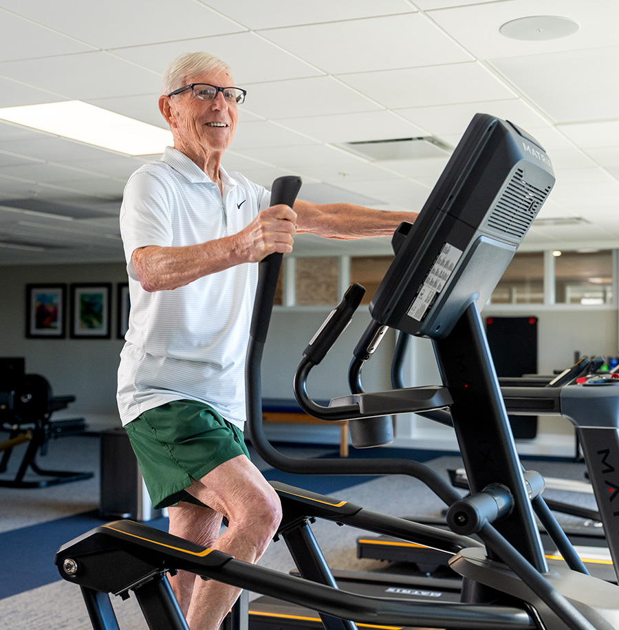 Senior man using exercise equipment in a fitness area of a residential community.