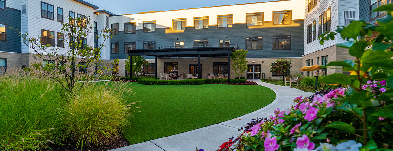 Modern senior living building with three floors and landscaped courtyard.