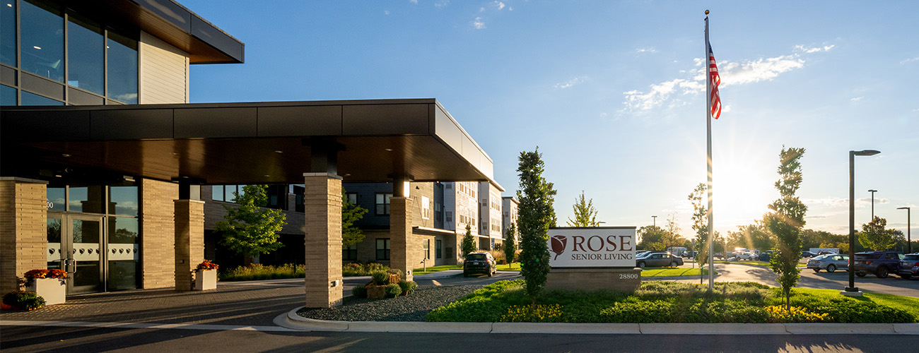 Modern building with large sign and flagpole in front yard during sunset.