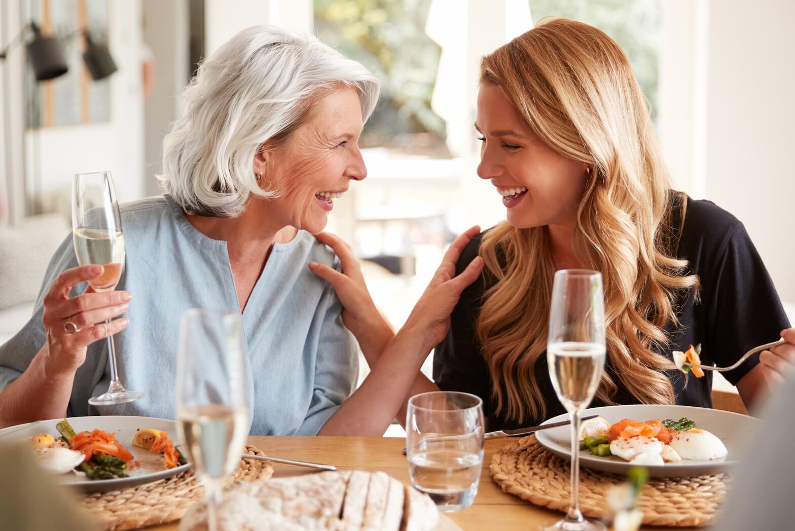Senior mother and adult daughter enjoying a glass of wine